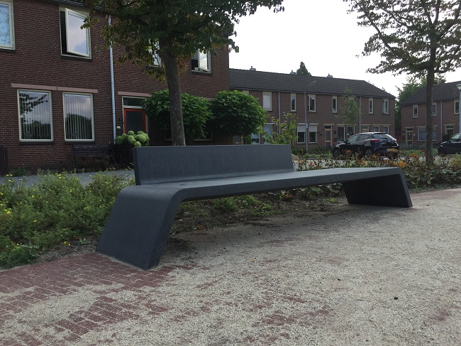 Een betonnen bankje met rugleuning.